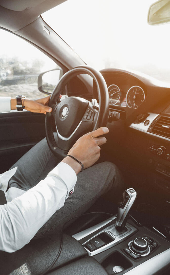 Man in business attire leaning on black car, using smartphone, representing RR – Buy & Sell Cars professional automotive marketplace.